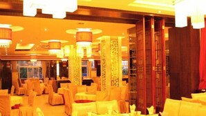 A banquet hall with round tables, chairs, and hanging lamps. - Fuhua Hotel (Pingwu)