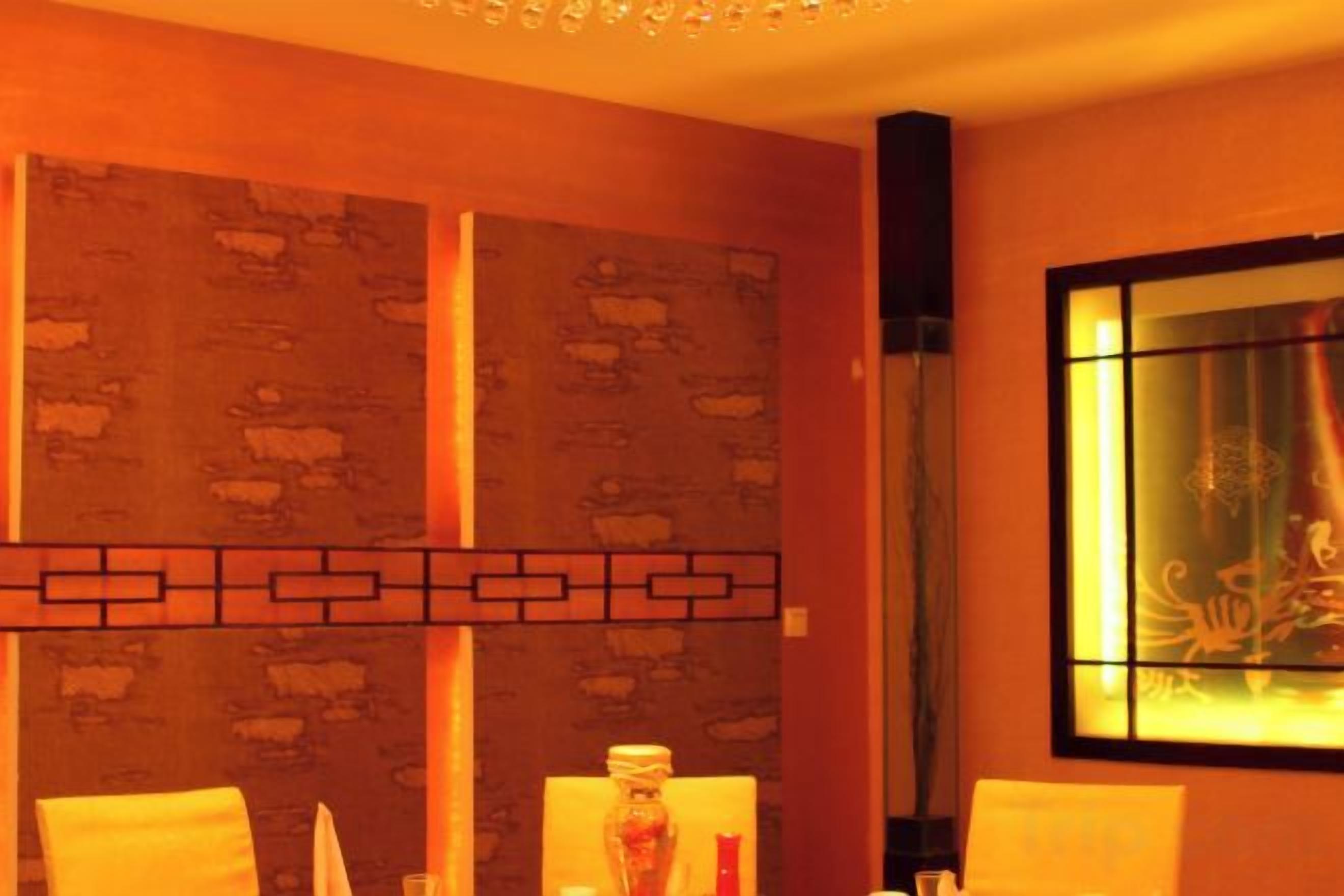 A room with a patterned wall, a decorative light fixture, and a window with a view.