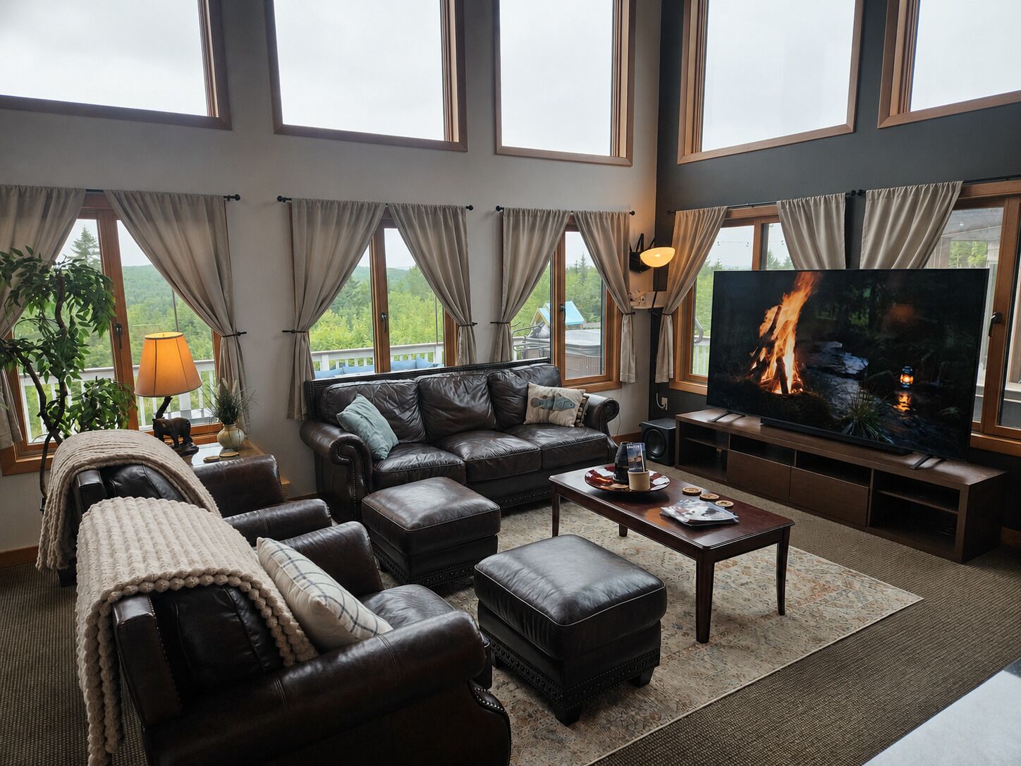 Ein geräumiges Wohnzimmer mit einer Ledersofa, Poufs, einem Couchtisch und einem großen Flachbildfernseher.