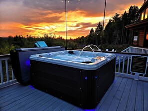 A hot tub on a wooden deck with a sunset view. - Bear Mountain Lodge (Robbinston)