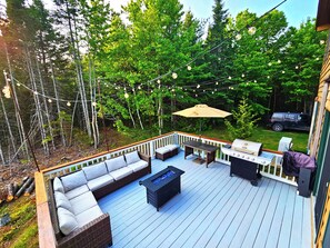 A deck with a sofa, a table, and a grill. - Bear Mountain Lodge (Robbinston)