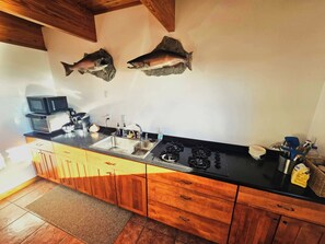 A kitchen with wooden cabinets, a stainless steel sink, and two fish mounted on the wall.