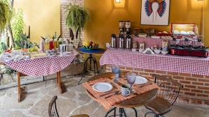 Un espacio de comedor al aire libre con manteles a cuadros, suelo de piedra y pared de ladrillo.