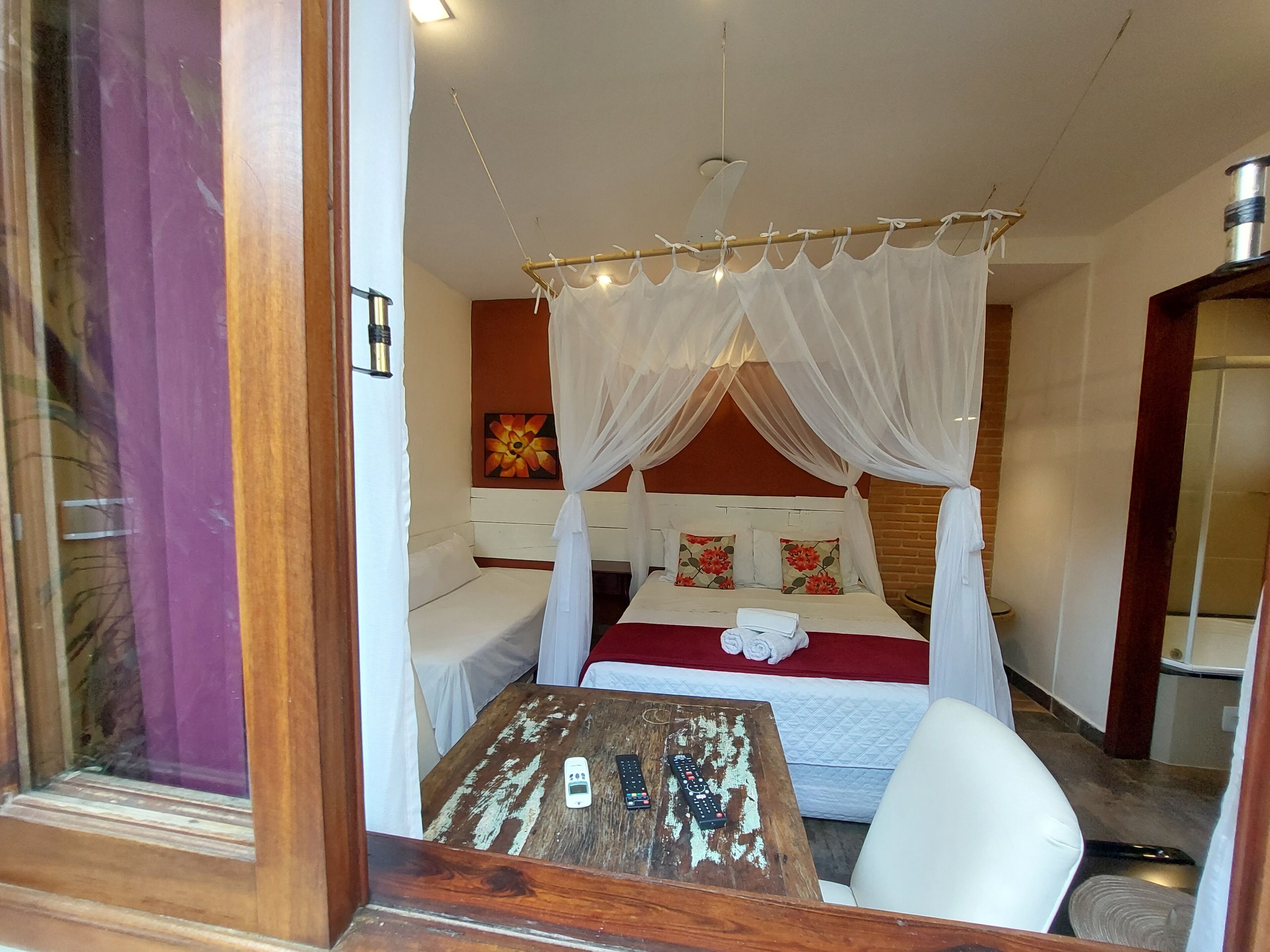 Una habitación con cama con dosel, una mesa de madera y un espejo.
