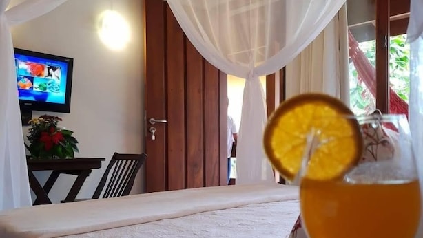 Un dormitorio con una cama, un vaso de jugo de naranja con una rodaja, uvas y una revista.