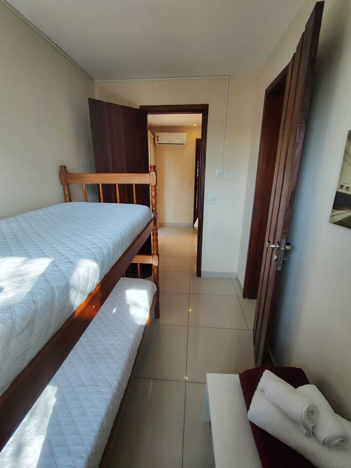 Una habitación pequeña y bien iluminada con una cama litera, una puerta de madera y una toalla sobre una mesa.