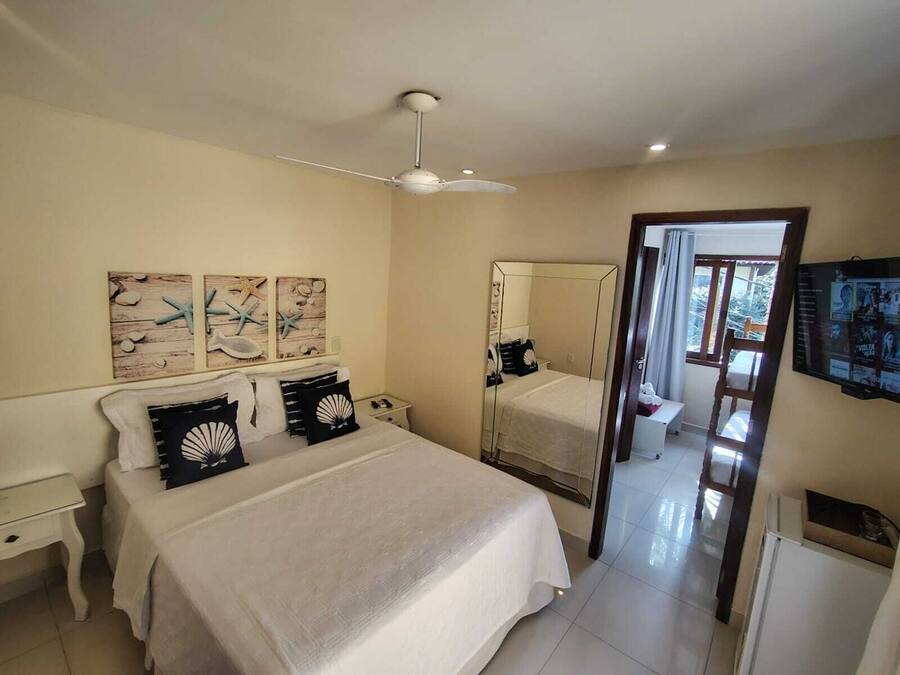Un dormitorio con cama, mesita de noche, espejo y cuadros en la pared.