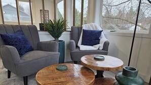 A modern living room with two grey sofas, a blue patterned pillow, a green plant, and a wooden coffee table with a green tray. - Modern Home with Game Room, Private Yard, Panoramic Views, 5B Sleeps 8+ (Spokane)