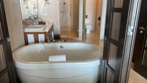 A modern bathroom with a large bathtub, a sink with a mirror, and a toilet.