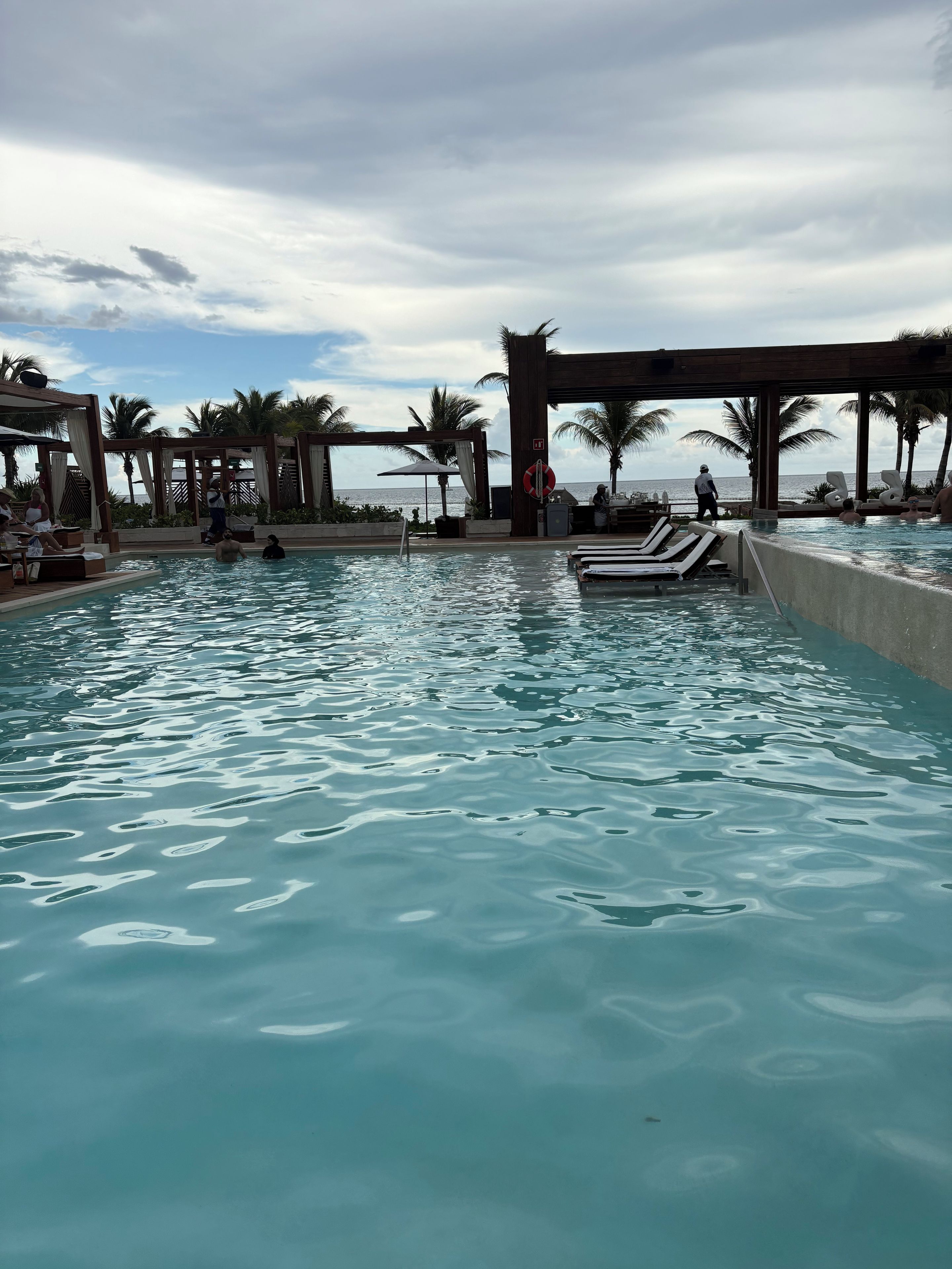 Una piscina con sillas de descanso y una pérgola de madera.