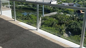 A balcony with a view of a cityscape, including buildings and greenery.