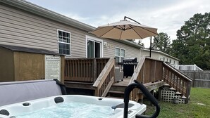 Un bain à remous avec une terrasse en bois et un espace patio couvert.