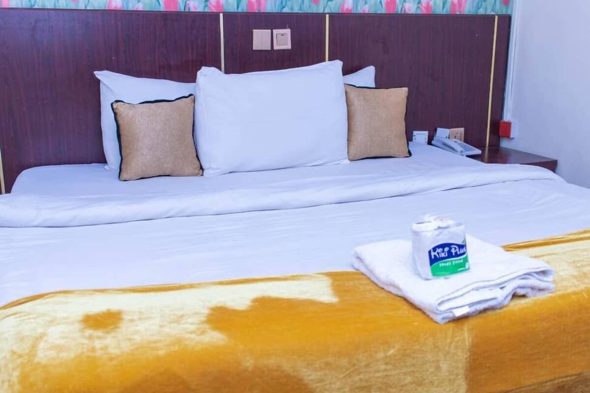 A hotel room with a bed, a nightstand, and a bottle of water.