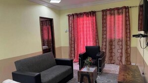 A living room with a sofa, armchair, and a small wooden table with a vase. - Apartment with View and Balcony B (Kunkajan-Jataya)