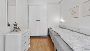 A bedroom with a white dresser, a bed with a gray blanket, a door, and a wall-mounted light. - 1 bedroom gorgeous apartment in Nexø (Nexø)