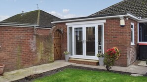 A two-story house with a brick exterior, a wooden front door, and a white-framed glass door.