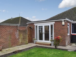 A two-story house with a brick exterior, a wooden front door, and a white-framed glass door.