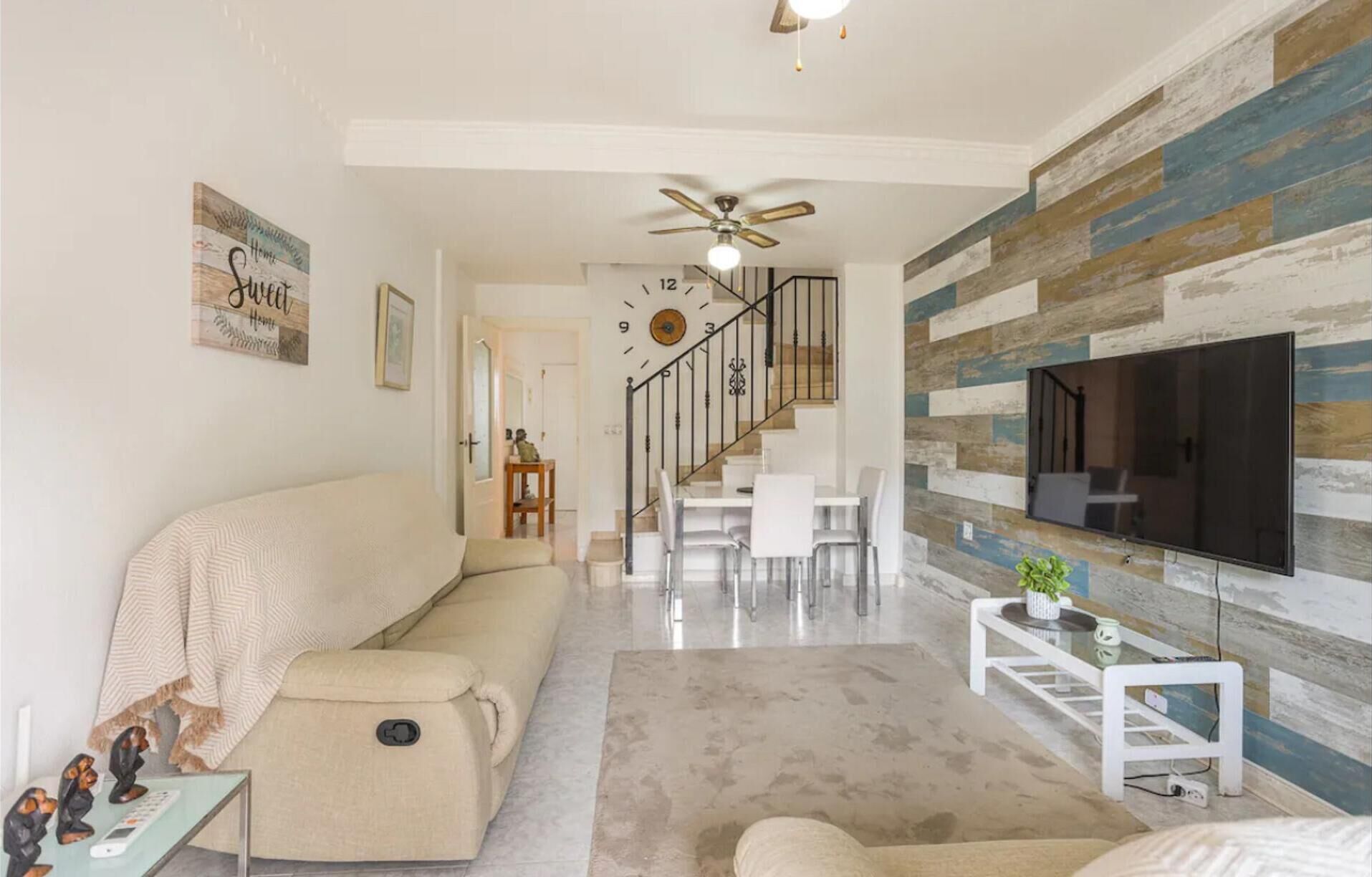A modern living room with a sofa, a coffee table, and a TV mounted on a wooden wall.