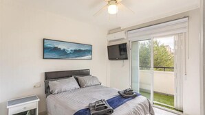 A bedroom with a bed, a television, a ceiling fan, a painting, and a balcony with a view. - Orihuela Costa, Sleeps 6 With Roof Terrace & Pool (Orihuela)