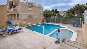 A swimming pool with blue lounge chairs, a tiled deck, and a building with balconies in the background. - Orihuela Costa, Sleeps 6 With Roof Terrace & Pool (Orihuela)