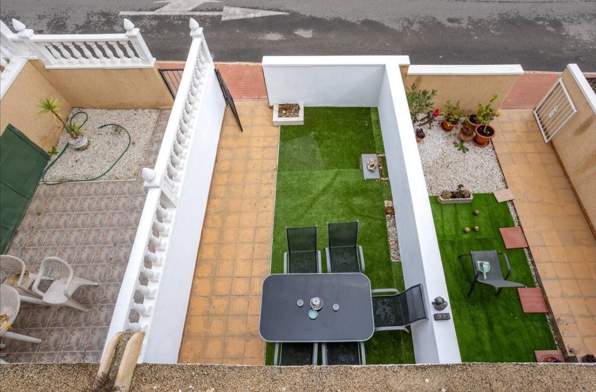 A rooftop patio with a small lawn, a table, and chairs.