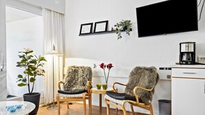 A modern living room with two chairs, a coffee maker, and a flat-screen TV mounted on the wall. - Awesome apartment in Nexø with WiFi (Nexø)