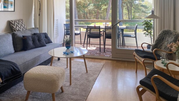 A living room with a sofa, ottoman, coffee table, and chairs. There is a sliding glass door leading to an outdoor patio with a table and chairs. - Awesome apartment in Nexø with WiFi (Nexø)
