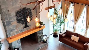 A modern living room with a stone fireplace, wooden beams, and a spiral staircase. - Charming Chalet in Tapalpa, Mexico with Game Lounge & Pet-Friendly Amenities! (Tapalpa)