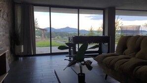 A spacious living area with a large sliding glass door leading to a balcony, a comfortable sofa, and a potted plant. - Charming Chalet in Tapalpa, Mexico with Game Lounge & Pet-Friendly Amenities! (Tapalpa)