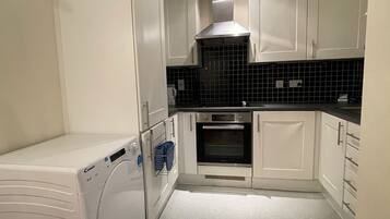 A compact kitchen with white cabinets, a built-in oven, and a washing machine.