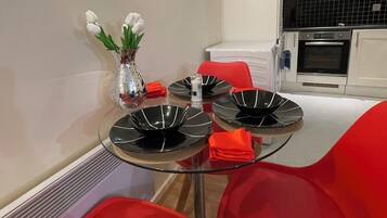 A modern kitchen with white cabinets, a black tiled backsplash, and a built-in oven.