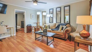 A living room with a sofa, coffee table, and a ceiling fan. - Charming 3-bedroom house in fabulous East Point with AC, WiFi (East Point)
