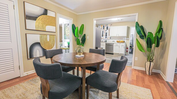 A dining area with a round table, six chairs, and two potted plants. - Charming 3-bedroom house in fabulous East Point with AC, WiFi (East Point)