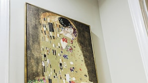 A framed Gustav Klimt painting, a modern lamp, and a potted plant on a table. - Charming 3-bedroom house in fabulous East Point with AC, WiFi (East Point)