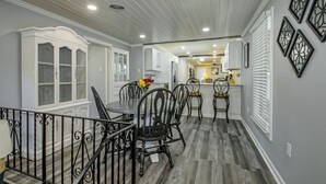A dining area with a table and chairs, a kitchen in the background, and decorative wall art. - IT’S FOOTBALL TIME AT THE HIDDEN TIGER! (Baton Rouge)