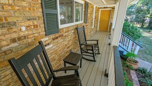 A covered porch with brick walls, a wooden bench, and a door. - IT’S FOOTBALL TIME AT THE HIDDEN TIGER! (Baton Rouge)