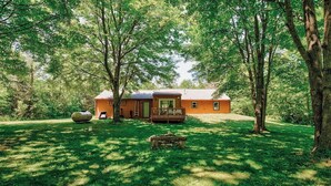 Un rustico chalet con facciata in legno, immerso nel verde e circondato da alberi.