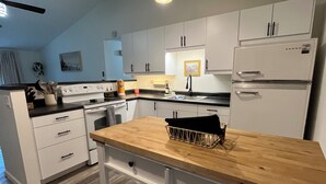 Una cucina moderna con mobili bianchi, un piano di lavoro in legno e un forno integrato.