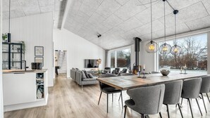 Een moderne keuken met een houten kookeiland, een eethoek met grijze stoelen en een groot raam met uitzicht op de omgeving.