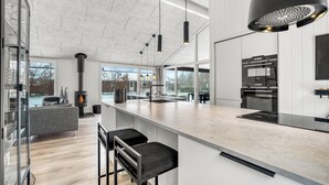 Een moderne keuken met een centraal eiland, een fornuis en een groot raam.