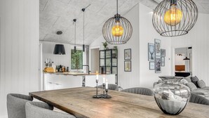 Een moderne keuken met witte kasten, een houten eettafel en hanglampen.