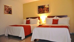 Een hotelkamer met twee bedden, elk met witte beddengoed en rode accenten, en een schilderij aan de muur.