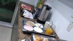 Een ontbijt opstelling met diverse etenswaren en een koffieapparaat op een keukenblad.