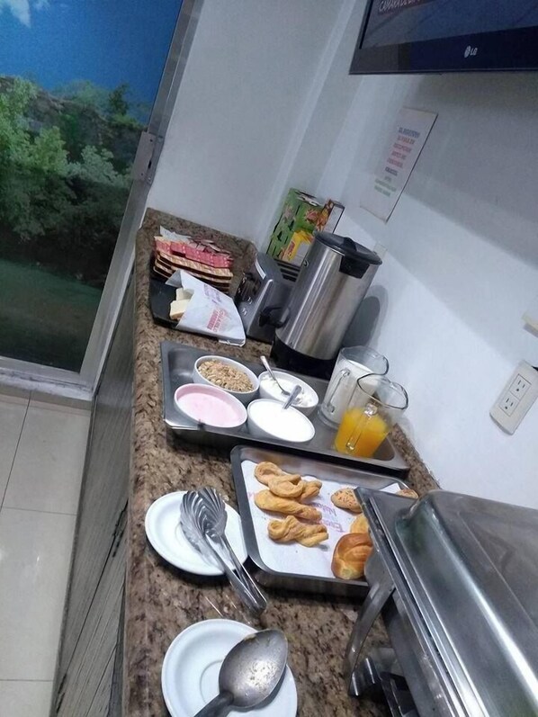 A breakfast setup with various food items and a coffee machine on a kitchen counter. - Hotel Yakar (Córdoba)