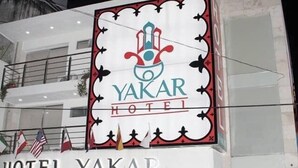 Het uiterlijk van Hotel Yakar, met een opvallend bord en de ingang.