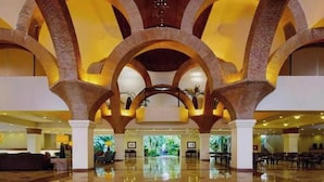 A spacious lobby with high ceilings and arched brick columns, featuring a central open area and seating arrangements. - Regal 3bd PH with private pool in Beach Resort Spa (Marina Vallarta, Puerto Vallarta)