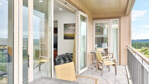 A balcony with a table and chairs, a painting on the wall, and a view of the landscape. - High Country Villa 250-Luxury Villa in Terrace Downs (Christchurch)