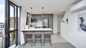 Une cuisine moderne dotée d’un grand îlot central, de tabourets de bar et offrant une vue par la fenêtre.
