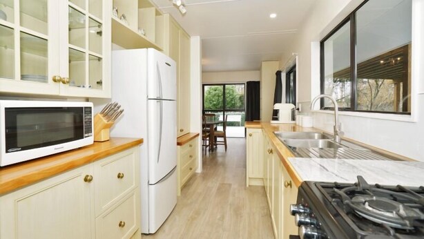 A modern kitchen with white cabinets, a built-in microwave, a refrigerator, a gas stove, and a large window providing natural light. - Narrows Hideaway-Rural retreat near Hamilton Airport (Christchurch)