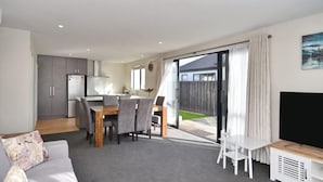 Un apartamento moderno con comedor, cocina, sala de estar y un balcón con vista al patio trasero.